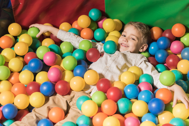 милий щасливий маленький хлопчик грає в басейні з барвистими кульками
 - Фото, зображення
