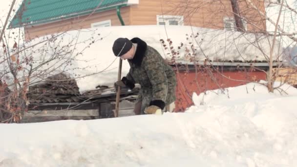 een man staat in de sneeuw in het dorp - Video