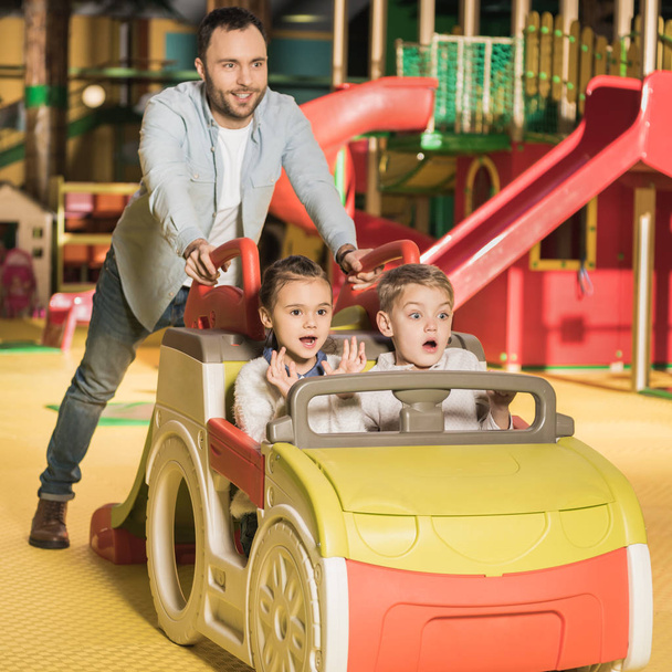 onnellinen isä kuljettaa lapsia lelu auto viihdekeskus
 - Valokuva, kuva