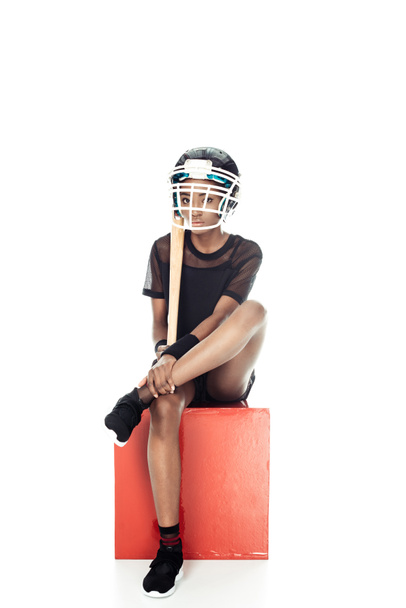 jugador de béisbol femenino con bate en casco protector sentado en cubo aislado en blanco
 - Foto, imagen