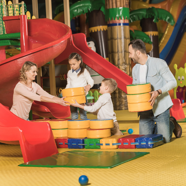 ευτυχισμένη οικογένεια με δύο μικρά παιδιά έπαιζαν μαζί σε κέντρο διασκέδασης   - Φωτογραφία, εικόνα