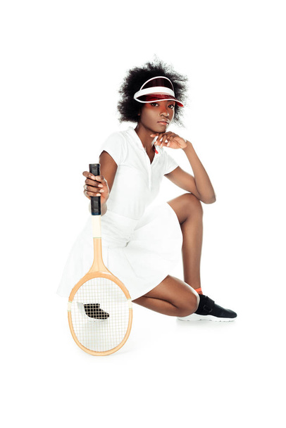 serious female tennis player with racket sitting on floor isolated on white - Φωτογραφία, εικόνα