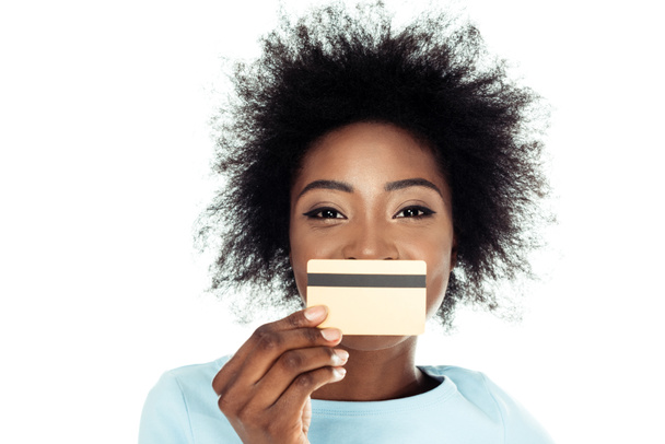 mujer joven sosteniendo la tarjeta de crédito de oro en frente de la cara aislado en blanco
 - Foto, Imagen