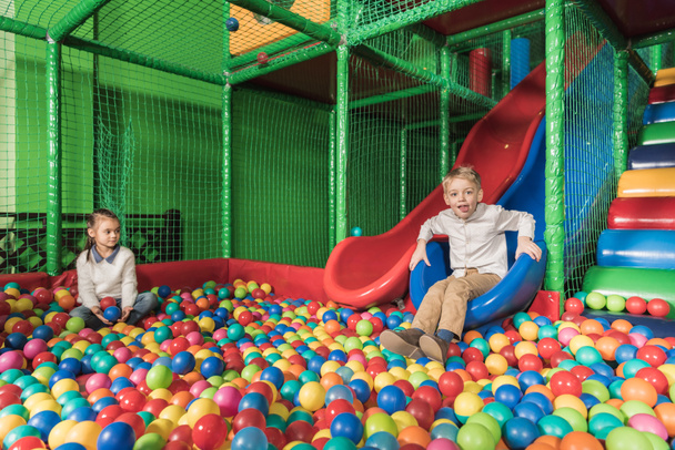 щасливі брати і сестри грають в басейні з барвистими кульками в розважальному центрі
 - Фото, зображення