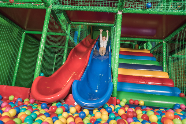 happy little boy sliding in pool with colorful balls - Photo, Image