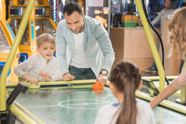 Schnappschuss einer Familie mit zwei Kindern beim gemeinsamen Airhockey im Spielcenter - Foto, Bild