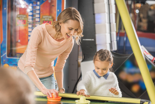 selective focus of happy mother and daughter playing air hockey in entertainment center  - Foto, imagen