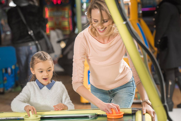 selective focus of beautiful happy mother and daughter playing air hockey  - Фото, зображення