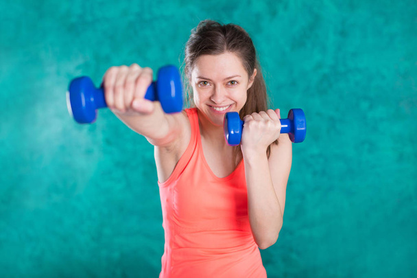 Sport fitness girl with dumbbells - isolated on the turquoise  background - Zdjęcie, obraz