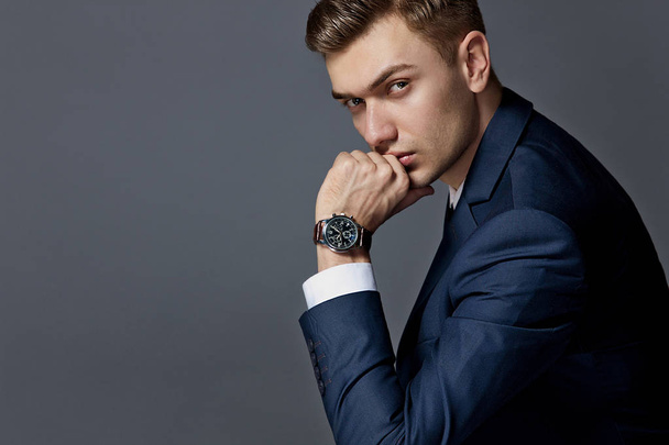 portrait of a man sitting with a suit with a watch, studio - Zdjęcie, obraz
