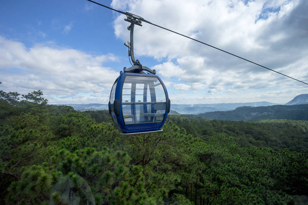 Malebné lanovka s barevnými kabiny nad horami se zelenými lesy s modrou oblohou v pozadí - Fotografie, Obrázek