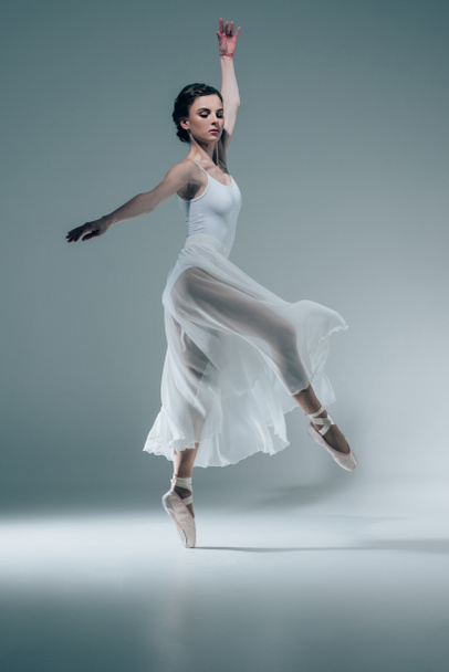 スタジオで踊る白いドレスで優雅なバレリーナ - 写真・画像