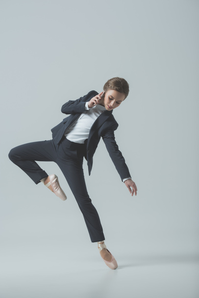 businesswoman in suit and ballet shoes dancing and talking on smartphone, isolated on grey - Foto, Imagem