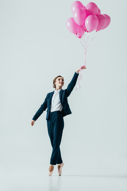 グレーに分離されたピンクの風船でジャンプ スーツとバレエ シューズの女性実業家 ロイヤリティフリー写真 画像素材