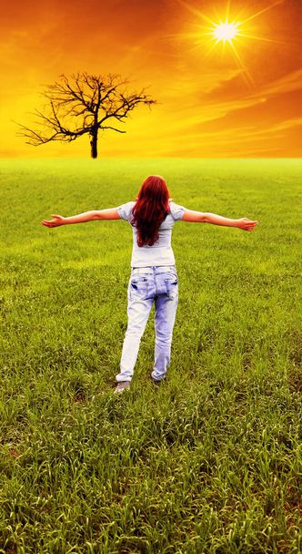 mujer feliz de pie en el campo verde. Manos arriba. vista trasera de una adolescente
 - Foto, Imagen