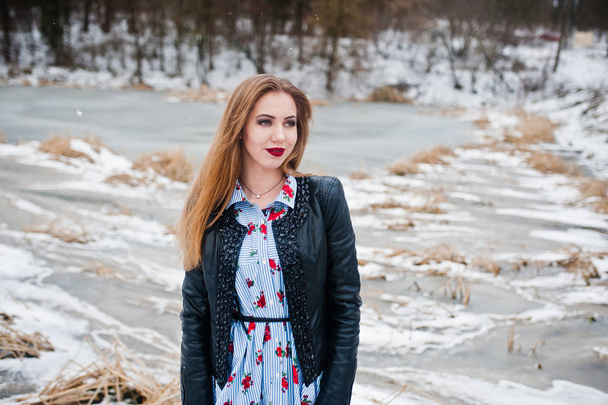 Stylish girl in leather jacket at winter day against frozen lake - Foto, imagen