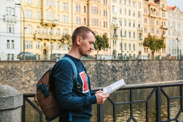 Turysta z plecakiem na tle starej architektury w Pradze w Czechach. Patrzy na mapie. - Zdjęcie, obraz