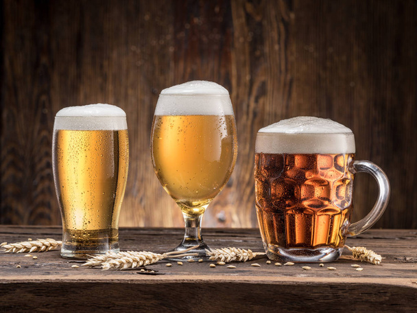 Different glasses of beer on the wooden table. - Фото, изображение