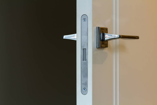 Modern stainless steel door handle on white wooden doors - Fotoğraf, Görsel