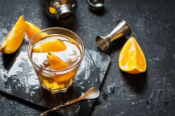 Un bicchiere di cocktail Negroni all'arancia e limone. Bevanda alcolica con rum e vermut sul tavolo di pietra scura
 - Foto, immagini