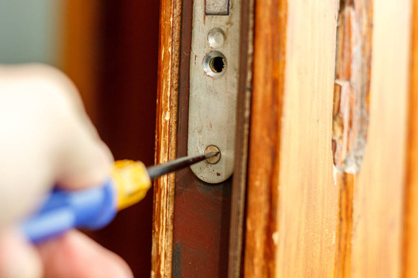 Κλειδαράς καθιστώντας την εγκατάσταση της κλειδαριά της πόρτας με κατσαβίδι - Φωτογραφία, εικόνα