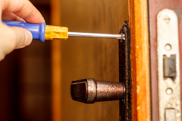 Ślusarz, Dokonywanie montażu zamka drzwi z śrubokręt - Zdjęcie, obraz