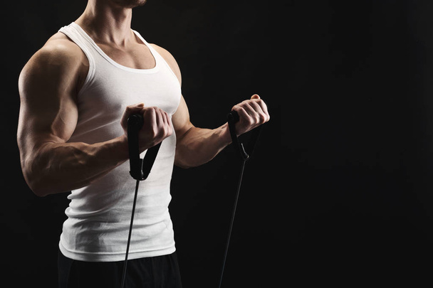 Athletic muscular man exercising with elastic expander at black - Fotoğraf, Görsel