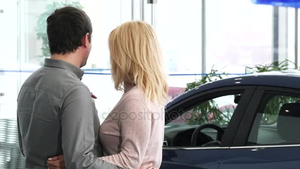 Vue arrière d'un couple d'âge mûr examinant une nouvelle voiture chez le concessionnaire
 - Séquence, vidéo