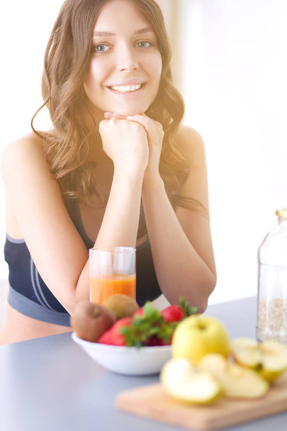 Girl sitting in the kitchen on the desk with fruit and glasses with juice. - Foto, Bild