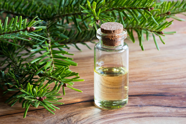 A bottle of fir essential oil with fir branches on a wooden tabl - Photo, Image