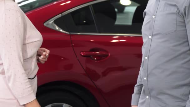 Tiro cortado de uma mulher recebendo chaves para seu novo automóvel na concessionária
 - Filmagem, Vídeo