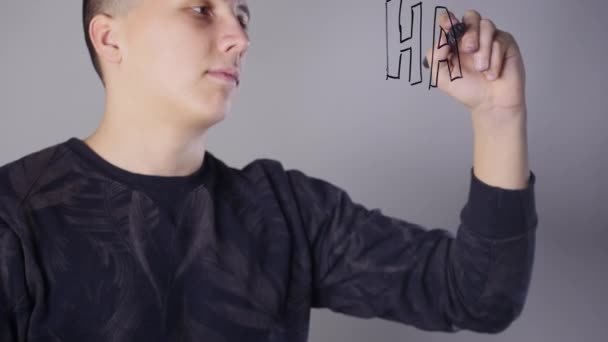 a young man paints on glass whiteboard - Materiał filmowy, wideo