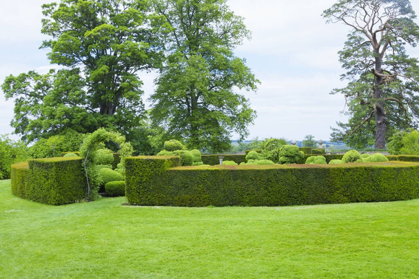 διαμορφωμένος κήπος με topiary ενότητα που περικλείεται από στολισμένα αντιστάθμισης και είσοδο μέσω τριαντάφυλλο καμάρα, καλοκαίρι στην Αγγλική εξοχή . - Φωτογραφία, εικόνα