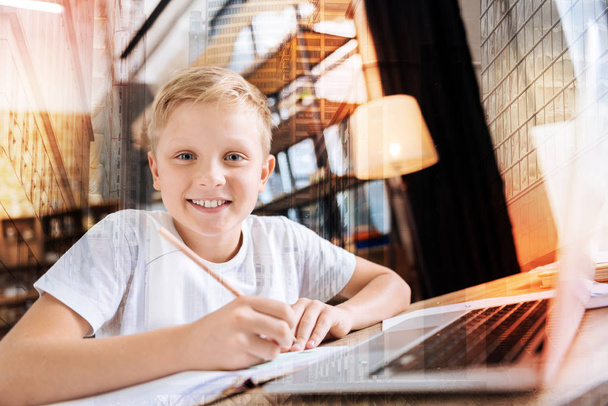 El niño positivo se siente contento al tomar notas frente a una computadora portátil
 - Foto, Imagen