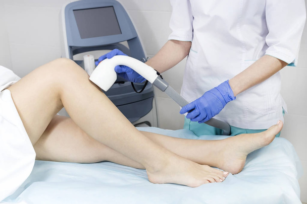 The process of laser depilation of female limbs in the beauty salon - Foto, imagen