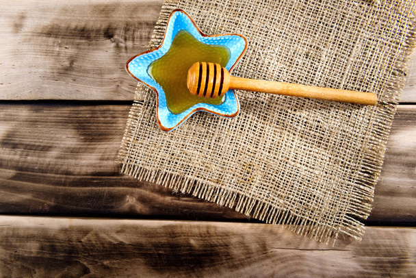 Honig im Teller mit Holzstäbchen für Honig auf Holzgrund. Ansicht von oben. - Foto, Bild