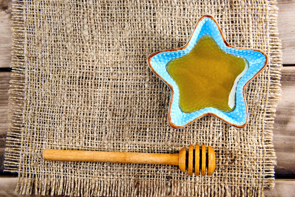 Honig im Teller mit Holzstäbchen für Honig auf Holzgrund. Ansicht von oben. - Foto, Bild