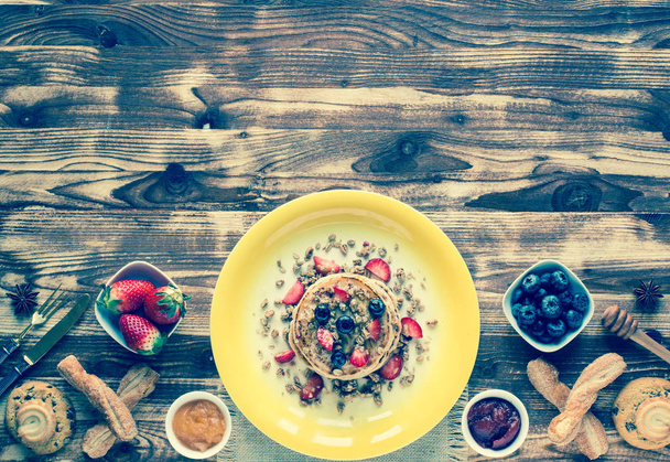 Homemade pancakes with fresh berries, strawberries, blueberries and maple syrup on a wooden background. Free space for text - 写真・画像