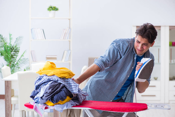 Jovem marido fazendo roupas de engomar em casa - Foto, Imagem