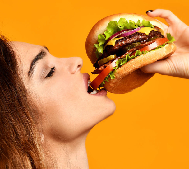 Woman eat burger sandwich with hungry mouth on yellow background - Foto, imagen
