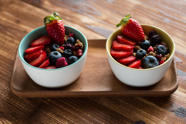 Cereal. Breakfast with muesli, and fresh fruits in bowls on a rustic wooden background, free space for text - 写真・画像