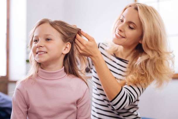 Cheerful mother making a hairdo for her little daughter - Foto, Imagen