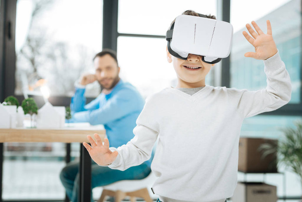 Cute boy trying out VR headset at fathers work - Photo, image