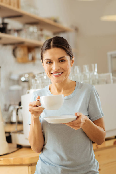 Cute pleasant lady holding a cup and smiling. - Foto, imagen