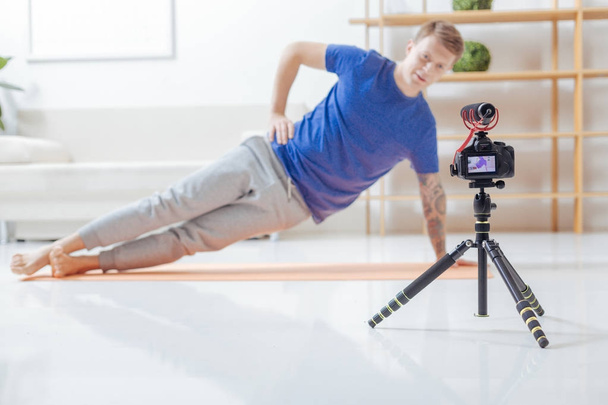 Concentrated video blogger doing exercises when looking into the camera - Foto, Imagem