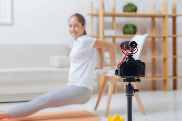 Smiling trainer doing chair pushups and recording them on a camera - Foto, Imagem