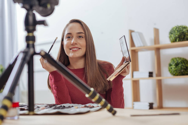 Enthusiastic beautiful woman smiling to the camera while holding a brush - Photo, image