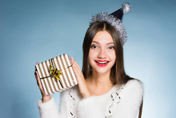 happy woman in a festive hat holds a gift in her hands - Φωτογραφία, εικόνα