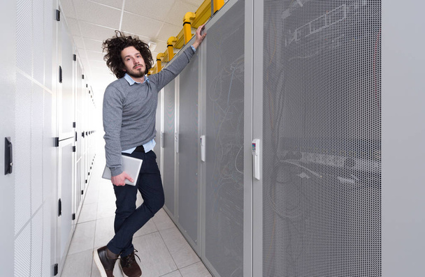 Männlicher IT-Ingenieur arbeitet im Serverraum eines modernen Rechenzentrums an einem Tablet-Computer - Foto, Bild