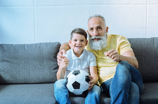 Excited grandchild and senior man watching football match - Valokuva, kuva